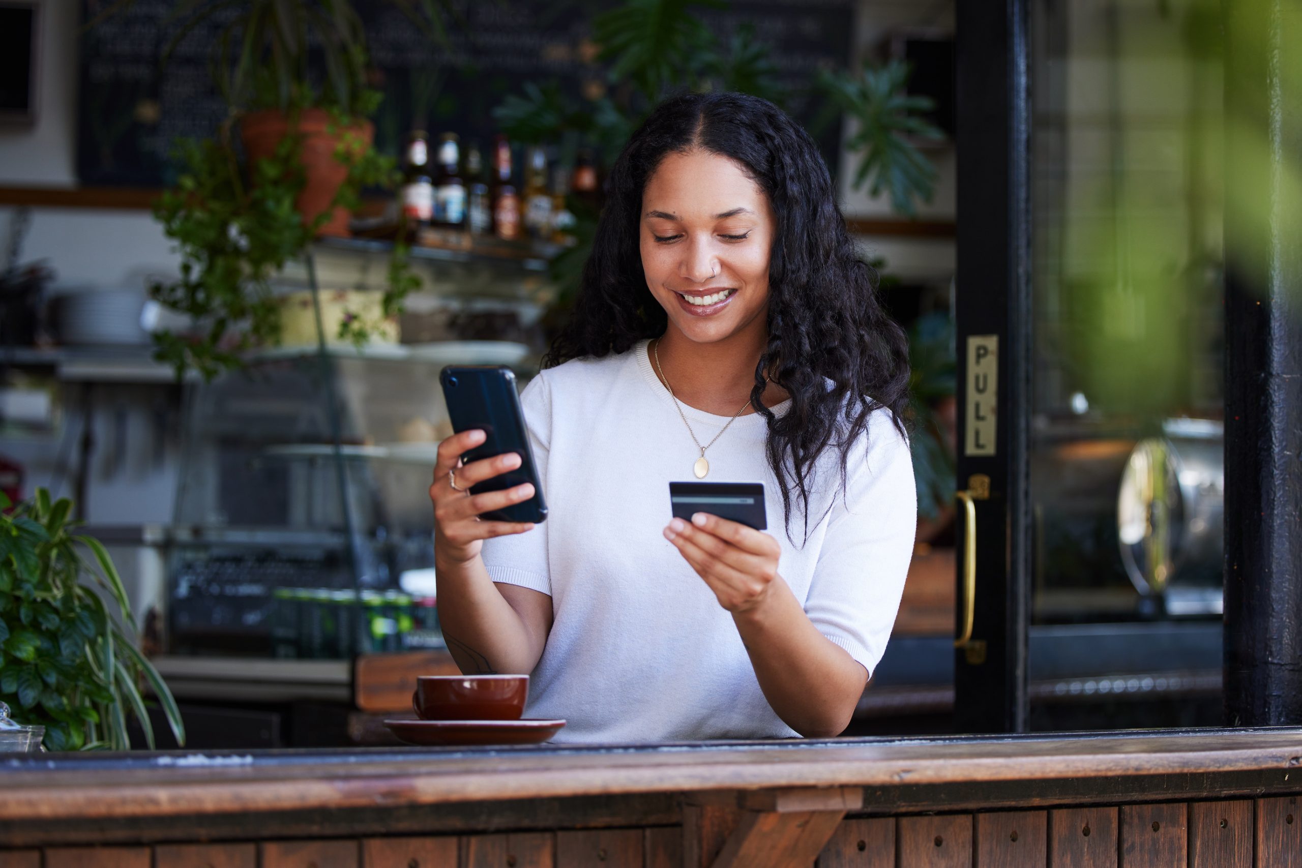 Woman holding phone and card to illustrate smart corporate cards